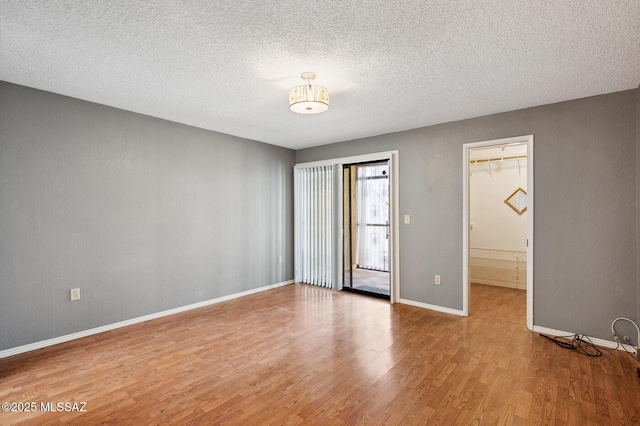 spare room with a textured ceiling, wood finished floors, and baseboards