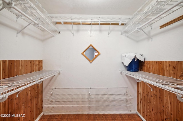 walk in closet featuring a bar and wood finished floors