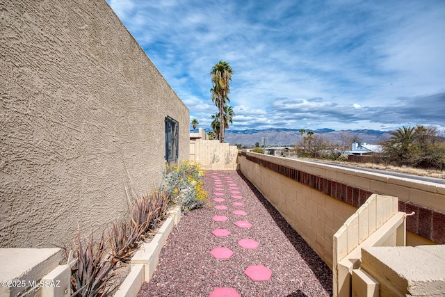 exterior space with fence, a mountain view, and stucco siding