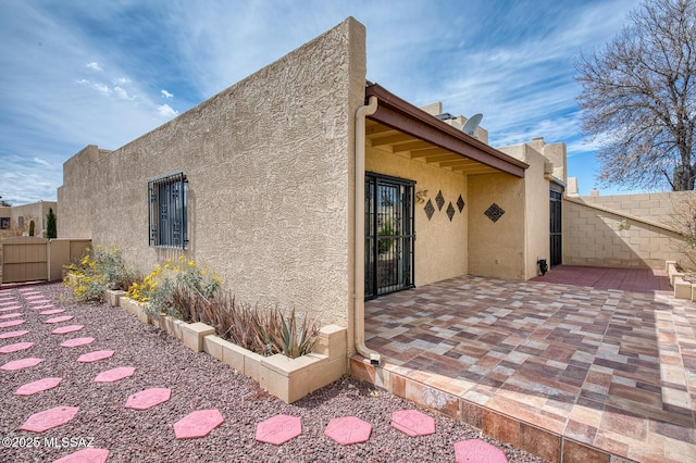 rear view of house with a patio area, a fenced backyard, and stucco siding