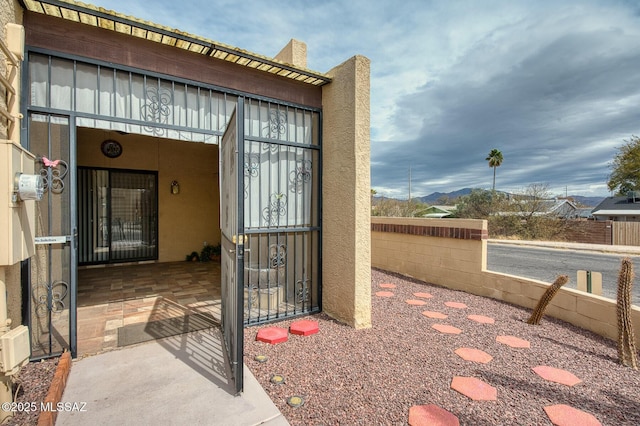 view of exterior entry featuring fence and stucco siding