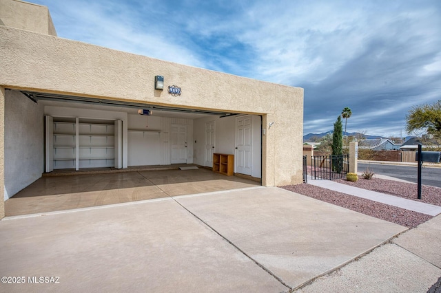 garage with a gate, fence, and concrete driveway