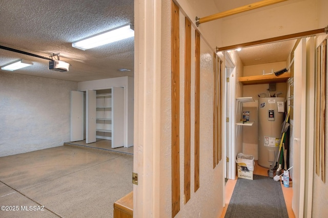 basement featuring a garage, water heater, and a textured ceiling