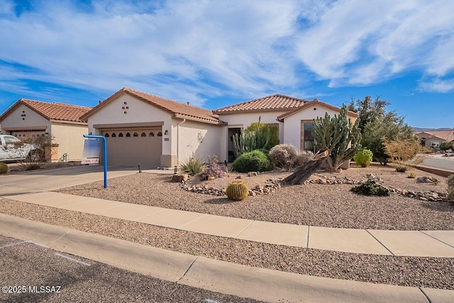 mediterranean / spanish-style house with a garage, driveway, a tile roof, and stucco siding