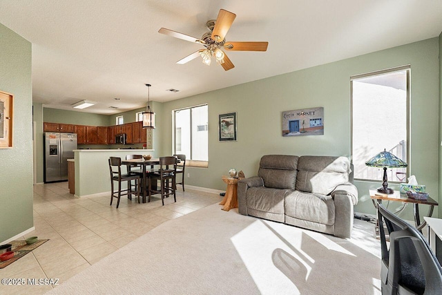 living room featuring light tile patterned floors, ceiling fan, and baseboards