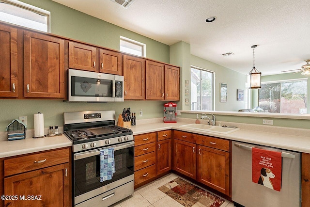 kitchen featuring stainless steel appliances, a sink, light countertops, and brown cabinets