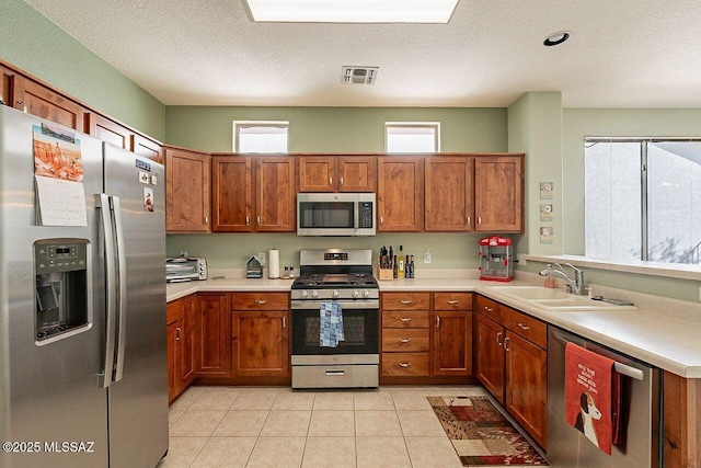 kitchen with appliances with stainless steel finishes, brown cabinets, and a sink