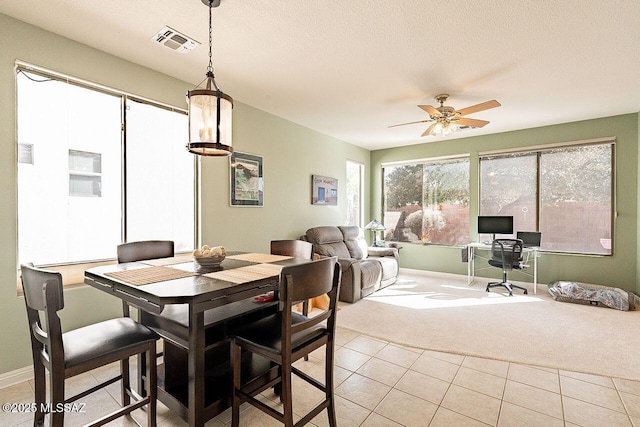 dining area with light carpet, light tile patterned floors, visible vents, and baseboards