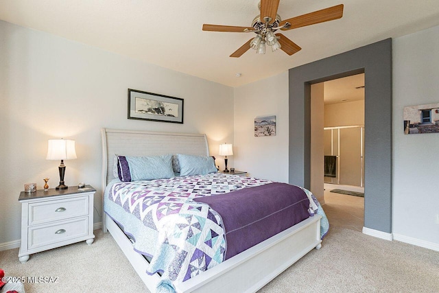 bedroom with a ceiling fan, light carpet, ensuite bath, and baseboards