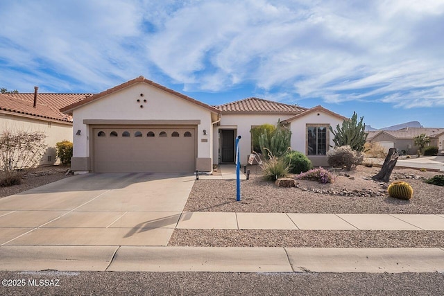 mediterranean / spanish home featuring driveway, a tiled roof, an attached garage, and stucco siding