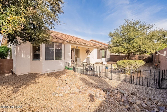 view of front of home with a fenced backyard, a patio, a tiled roof, and stucco siding