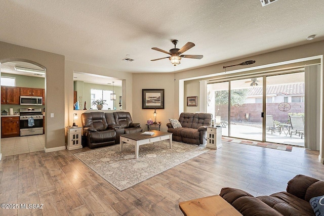 living area with a ceiling fan, visible vents, a textured ceiling, and light wood finished floors