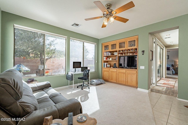 living area with light tile patterned floors, baseboards, visible vents, a ceiling fan, and light colored carpet