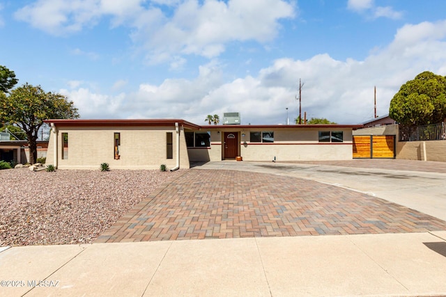 single story home featuring decorative driveway and fence