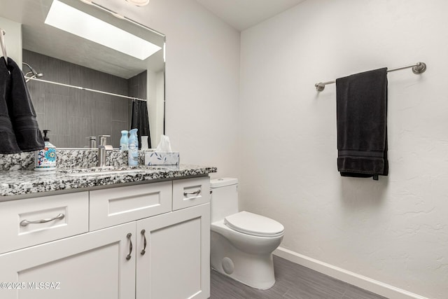 bathroom with baseboards, toilet, a shower with curtain, wood finished floors, and vanity