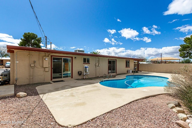 rear view of property featuring fence, a fenced in pool, and a patio