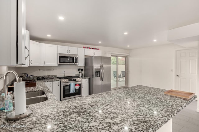 kitchen featuring a peninsula, light stone countertops, appliances with stainless steel finishes, and white cabinets