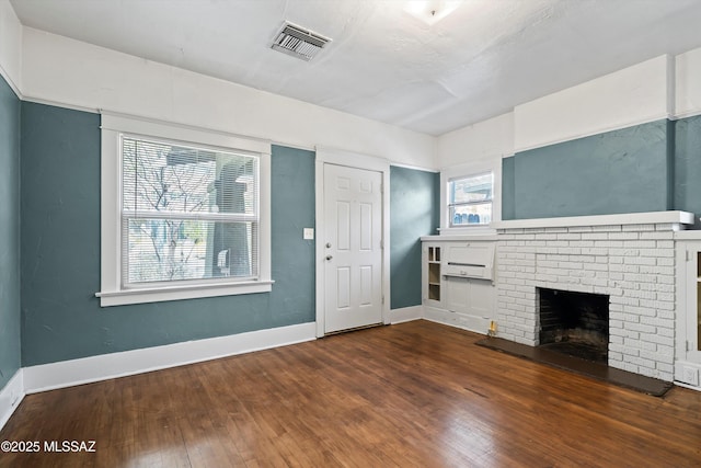 unfurnished living room with a brick fireplace, baseboards, visible vents, and hardwood / wood-style floors