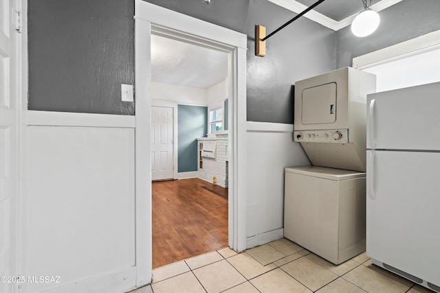 laundry area with stacked washer / drying machine, laundry area, and light tile patterned floors