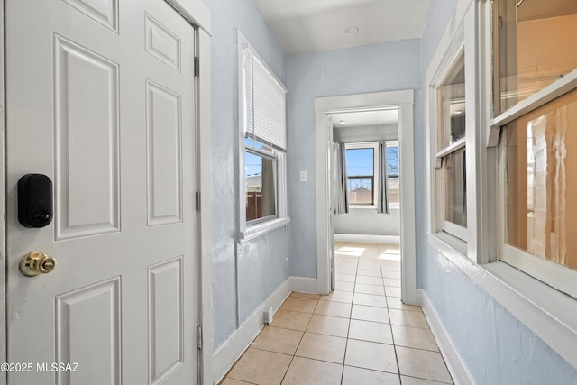 hall featuring light tile patterned flooring and baseboards