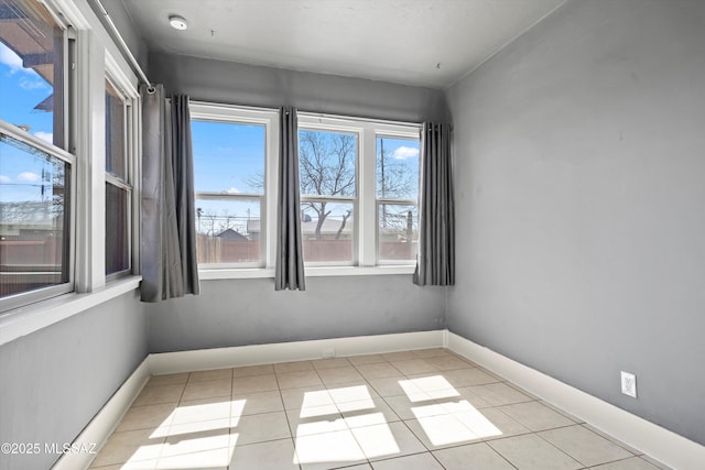 tiled spare room featuring baseboards