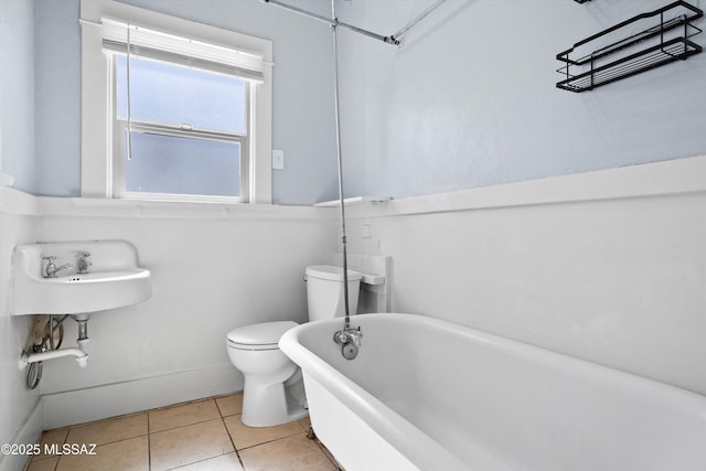 bathroom featuring a soaking tub, tile patterned flooring, and toilet