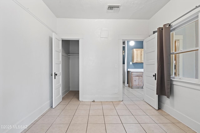 unfurnished bedroom featuring a closet, visible vents, baseboards, and light tile patterned flooring