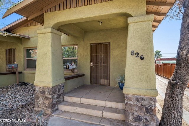 doorway to property featuring a patio, fence, and stucco siding