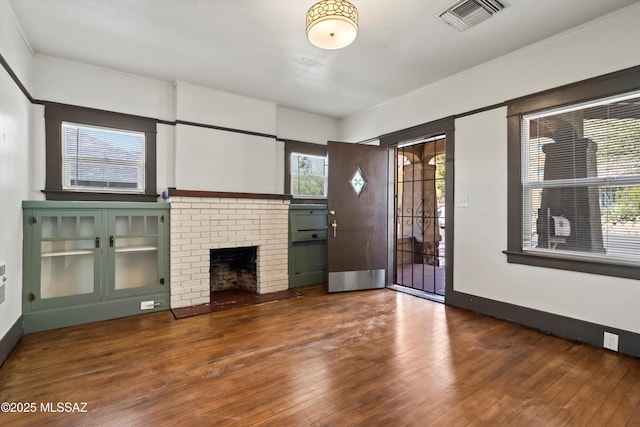 unfurnished living room featuring hardwood / wood-style flooring, a fireplace, and visible vents