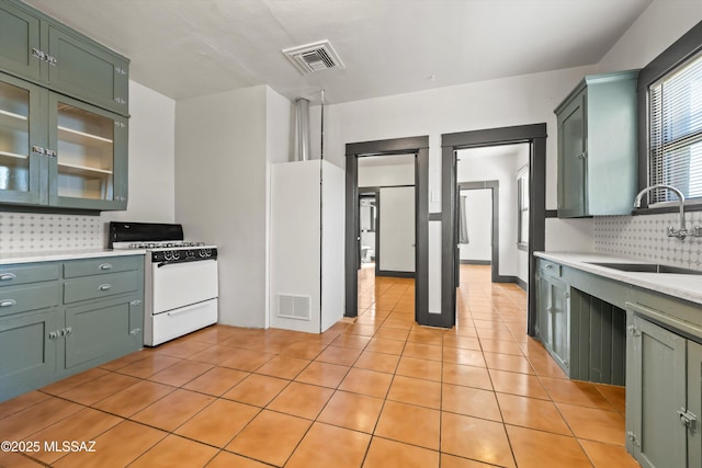 kitchen with a sink, visible vents, green cabinetry, and gas range gas stove