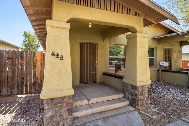 doorway to property with fence and stucco siding