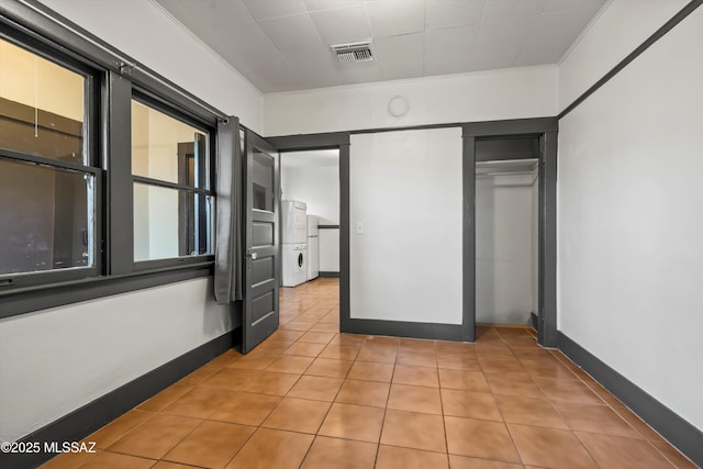 unfurnished bedroom featuring baseboards, visible vents, crown molding, a closet, and light tile patterned flooring