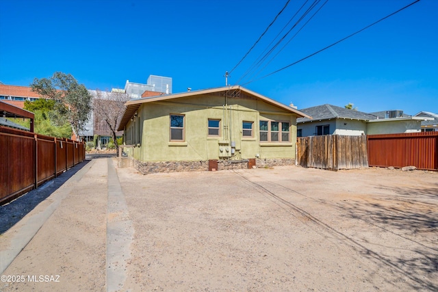 rear view of house with fence and stucco siding