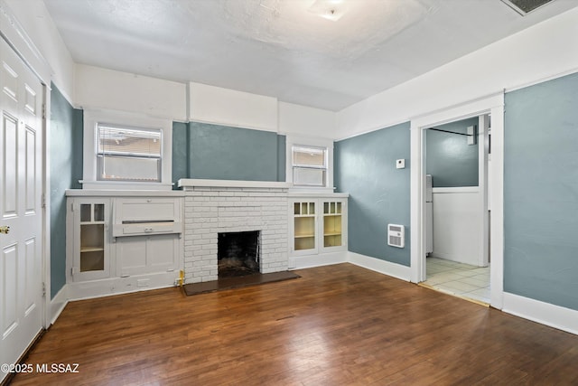 unfurnished living room featuring hardwood / wood-style floors, a fireplace, and baseboards