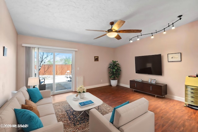 living area featuring a textured ceiling, wood finished floors, baseboards, and ceiling fan