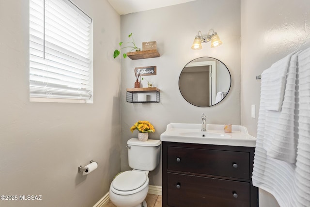 half bath with baseboards, toilet, and vanity