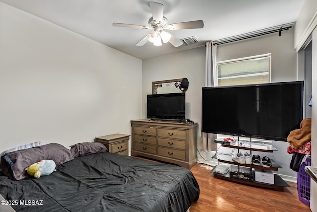 bedroom with visible vents, wood finished floors, and a ceiling fan