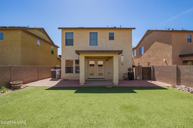 rear view of house with french doors, stucco siding, a fenced backyard, a patio, and a lawn