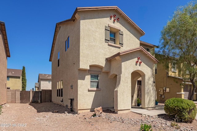 view of front facade featuring stucco siding, a gate, and fence
