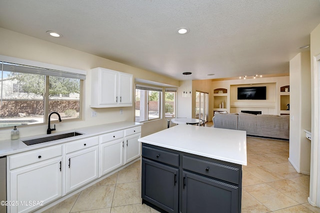 kitchen featuring light countertops, white cabinetry, a sink, and a fireplace