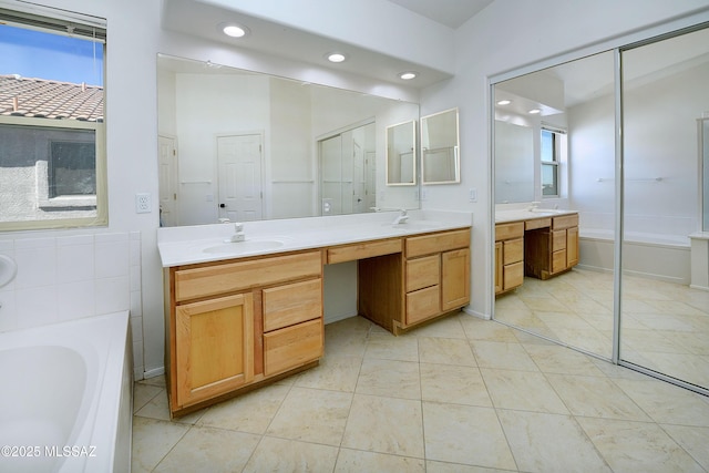 full bathroom with double vanity, a sink, a bath, and recessed lighting