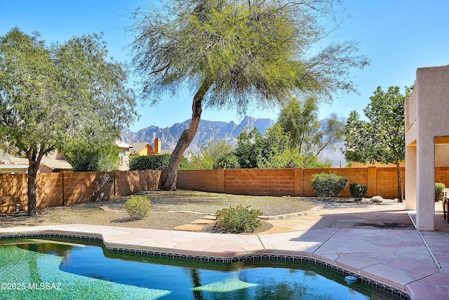 view of swimming pool featuring a mountain view, a patio, a fenced backyard, and a fenced in pool