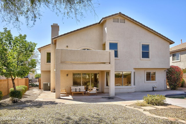 rear view of property with a balcony, a patio area, fence, and stucco siding