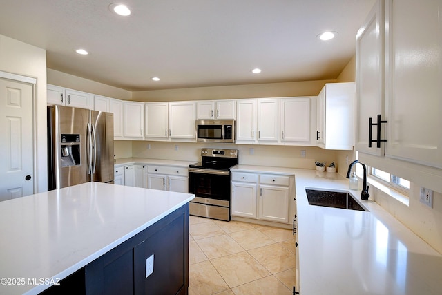 kitchen with appliances with stainless steel finishes, white cabinets, a sink, and light tile patterned flooring