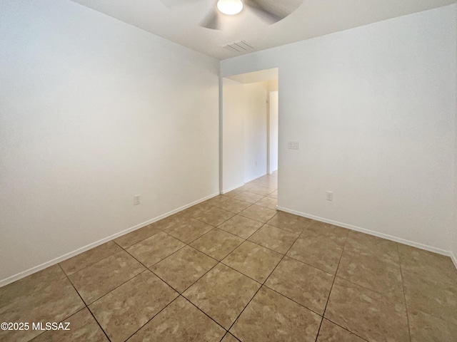 tiled empty room featuring baseboards, visible vents, and a ceiling fan