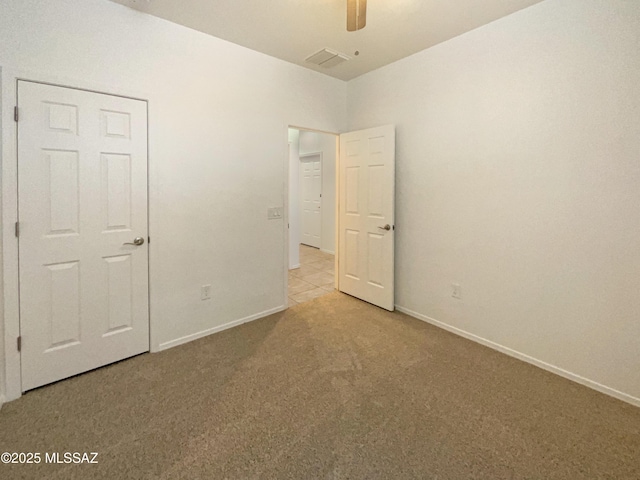 empty room featuring ceiling fan, carpet floors, visible vents, and baseboards