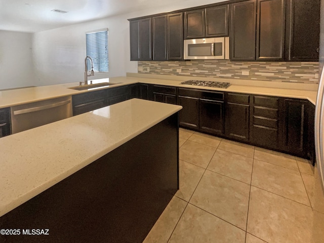 kitchen with light tile patterned floors, light stone counters, appliances with stainless steel finishes, a sink, and backsplash