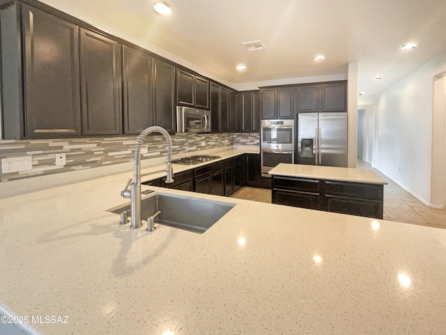 kitchen with visible vents, appliances with stainless steel finishes, light stone counters, and a sink