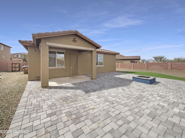 back of property featuring a patio area, a fenced backyard, a fire pit, and stucco siding