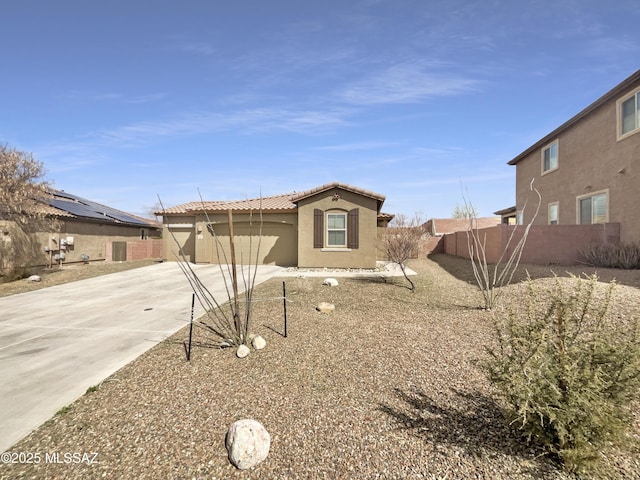 view of front of property with an attached garage, fence, driveway, a tiled roof, and stucco siding